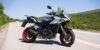 Suzuki GSX-S1000GX 2026 σε γκρι και μαύρο με κόκκινους τροχούς, σταθμευμένη σε ορεινό δρόμο