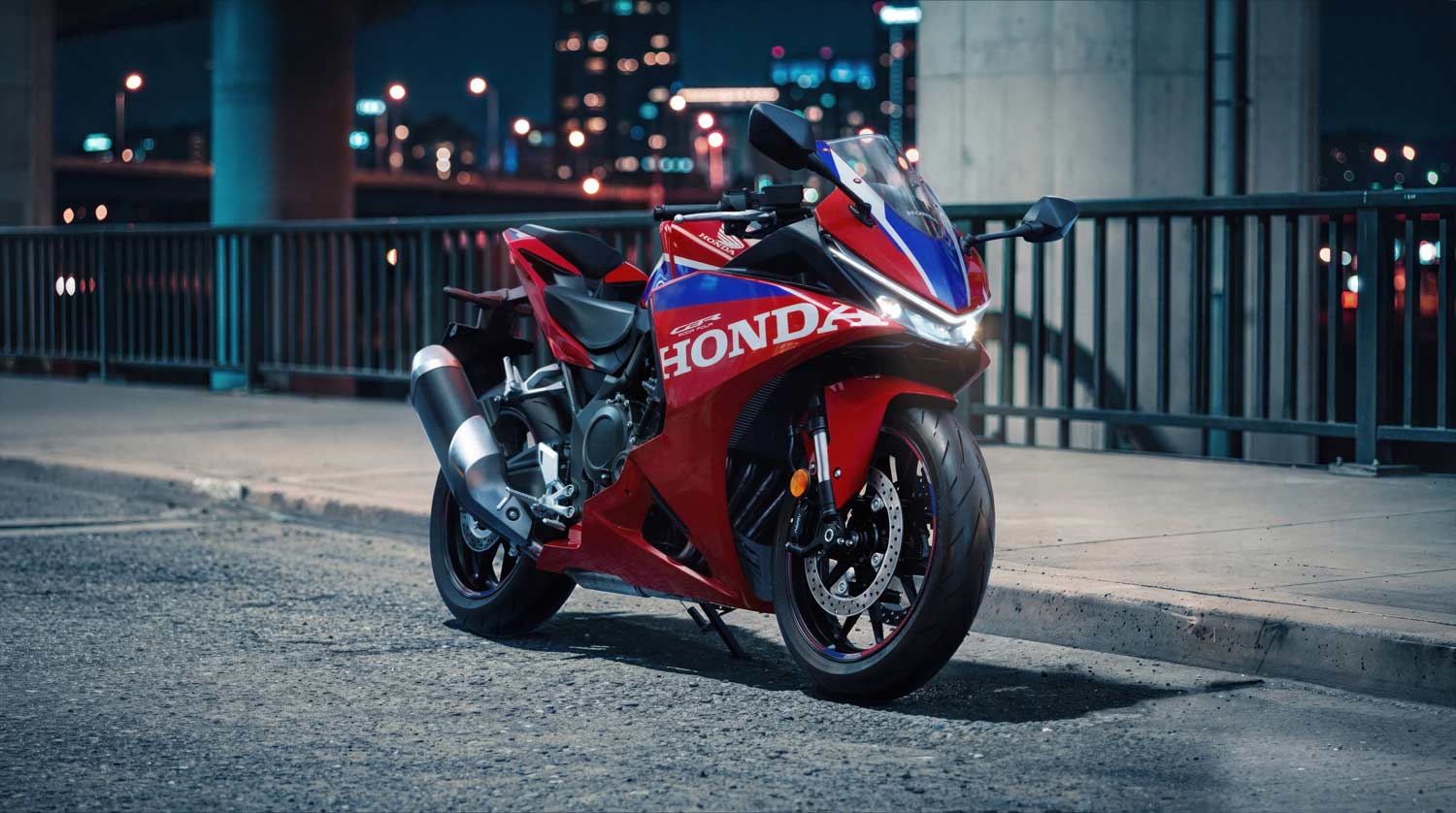 Honda CBR500R FOUR 2027 με αναμμένους προβολείς LED σε αστικό δρόμο τη νύχτα