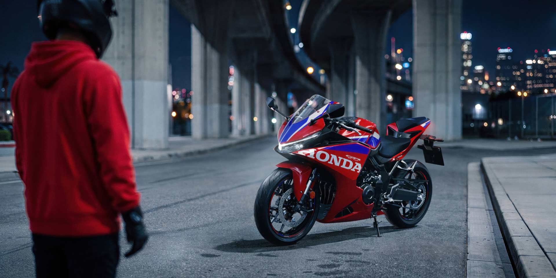 Honda CBR500R FOUR 2027 σε Ignition Red Tricolour παρκαρισμένη κάτω από γέφυρα στην πόλη τη νύχτα