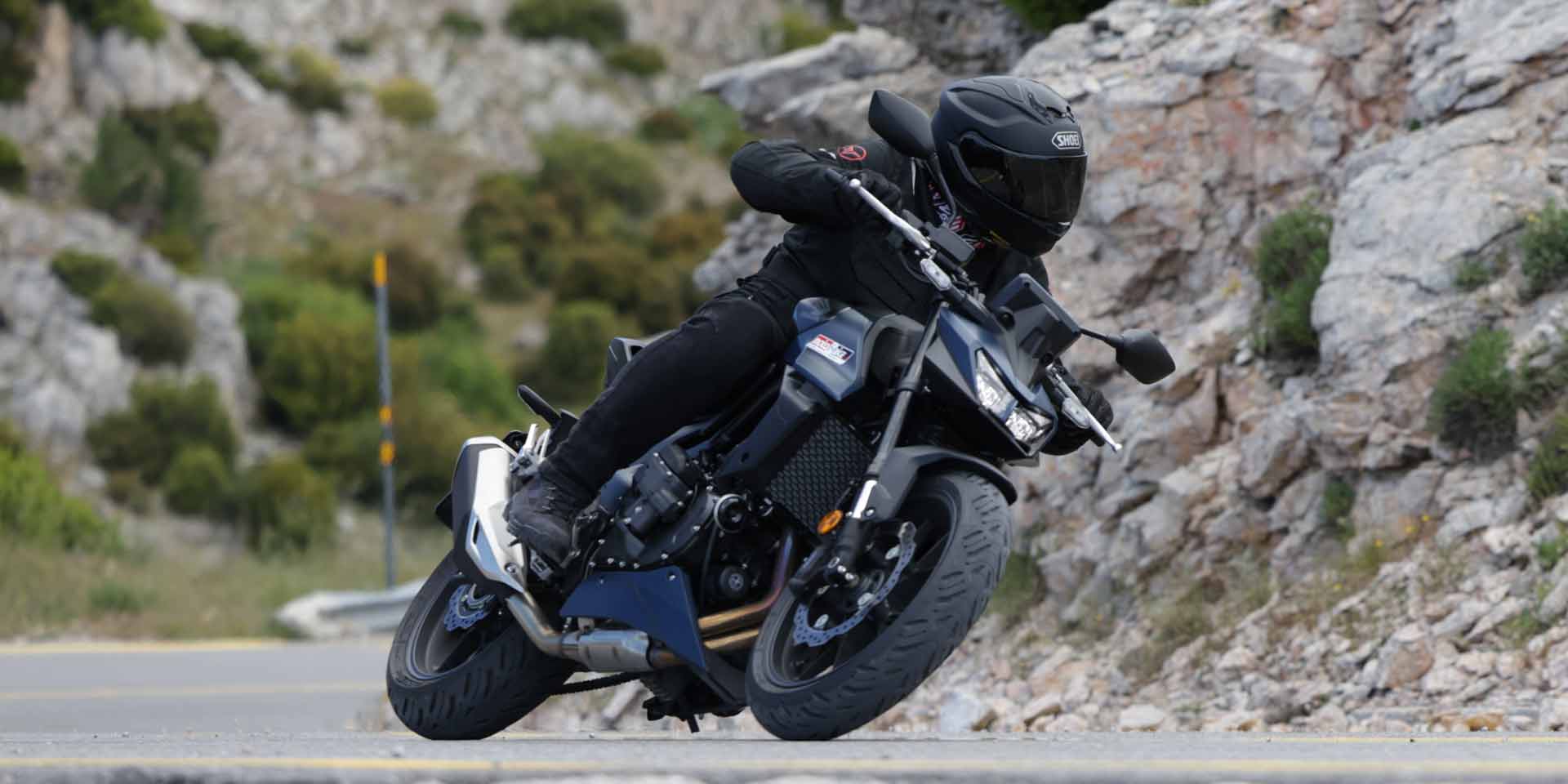 Honda CB750 Hornet E-Clutch σε στροφή σε ορεινό δρόμο, με αναβάτη με μαύρο εξοπλισμό